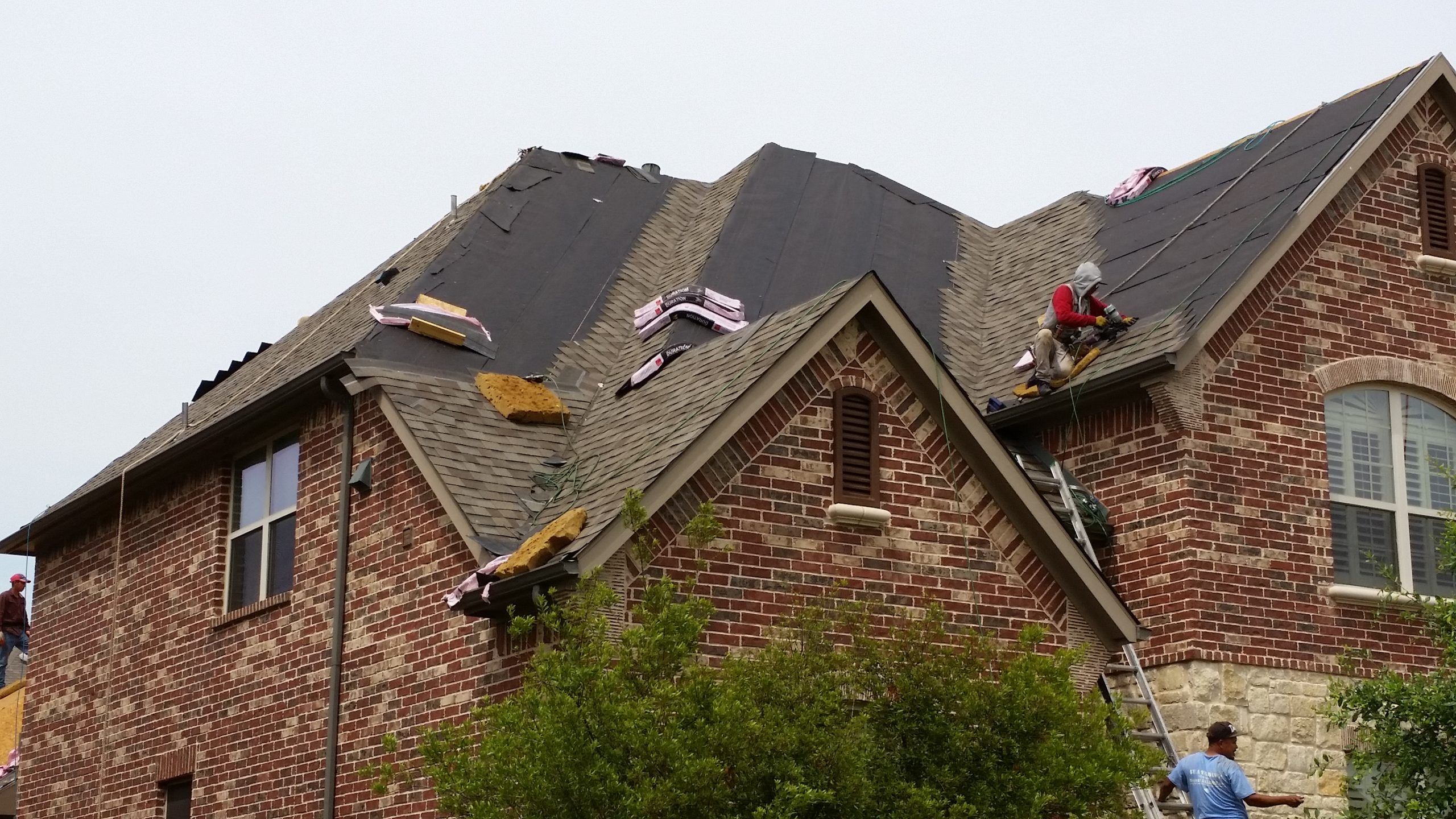 A team of roofers adding shingles to a repaired roof