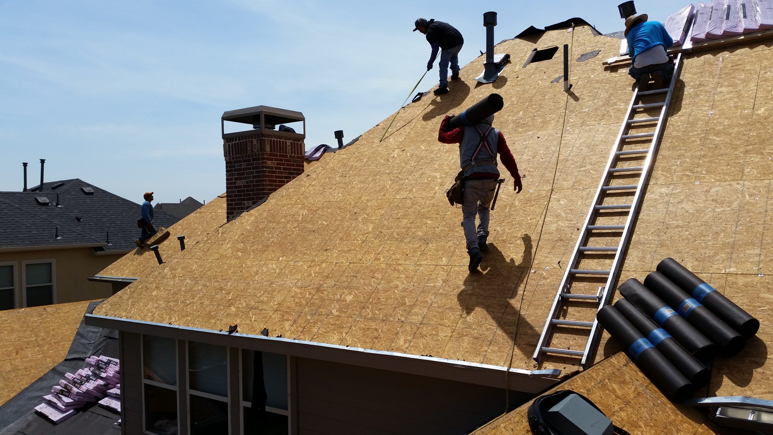 A team of roofers adding shingles to a repaired roof